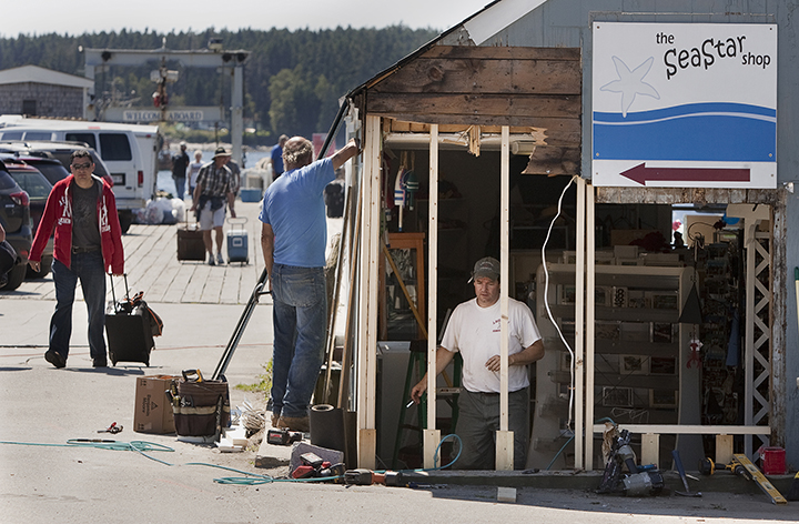 Tim Harris and Joseph Richardi of Port Clyde repairs the damage on Monday to a shop at the scene of a fatal auto pedestrian accident on Sunday at the wharf in Port Clyde.