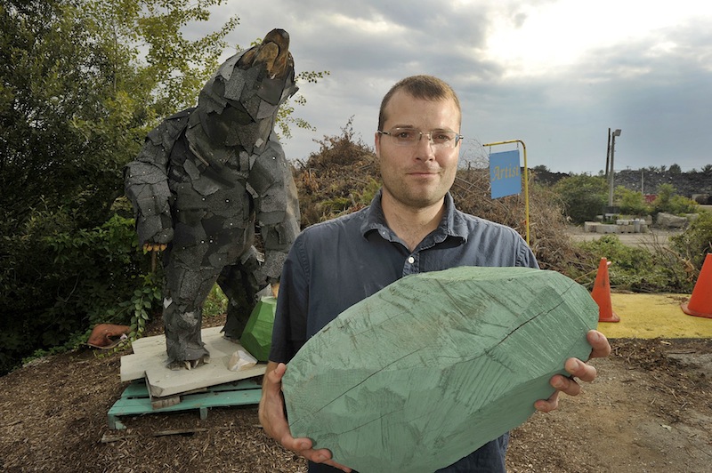 Local artist Andy Rosen is completing an artist-in-residency at the Scarborough Recycling Center. He has created a 7-foot-tall black bear out of found materials at the dump. Rosen is holding one of the wooden "rocks" he made for the exhibit.