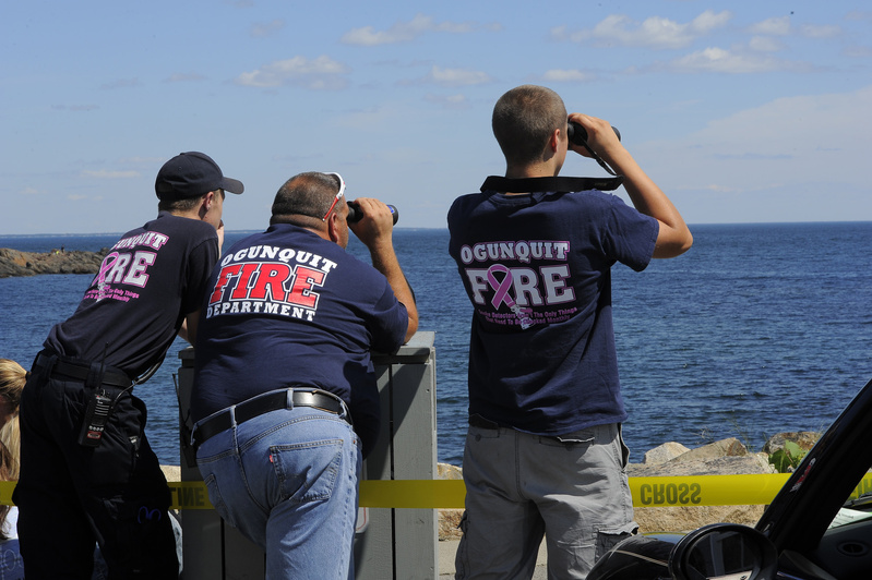 Tom Cryer, Gus Dunham and Jordan Moore of the Ogunquit Fire Department watch from shore Friday as searchers work the waters of Perkins Cove looking for a local fishermen who went missing Thursday night from a boat. Search2
