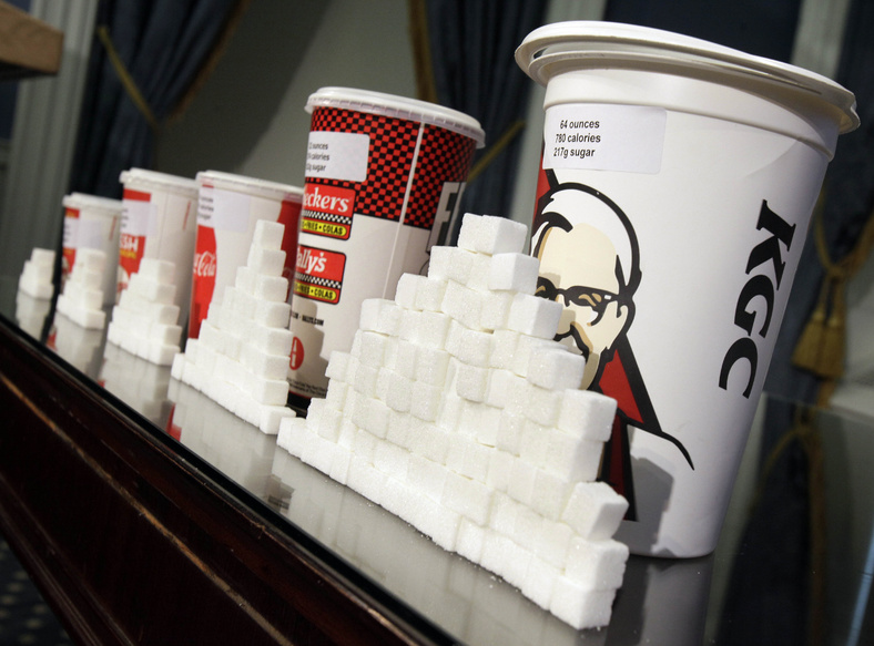 Various sizes of soft drink cups are displayed next to stacks of sugar cubes. A new study using mice found that the mouse equivalent of just three sugary sodas a day had significant negative effects on life span and competition for mates.