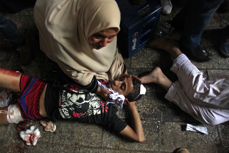 Egyptians lay on the ground after being injured during clashes between security forces and supporters of Egypt's ousted President Mohammed Morsi in Ramses Square, near the Al-Fath mosque, in Cairo, Egypt, Friday, Aug. 16, 2013. Gunfire rang out over a main Cairo overpass and police fired tear gas as clashes broke out after tens of thousands of Muslim Brotherhood supporters took to the streets Friday across Egypt in defiance of a military-imposed state of emergency following the country's bloodshed earlier this week. (AP Photo/Khalil Hamra)