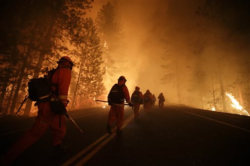 Inmate firefighters walk along state Highway 120 as crews continue to battle the Rim Fire near Yosemite National Park, Calif., on Sunday. Fire crews are clearing brush and setting sprinklers to protect two groves of giant sequoias.