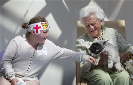 Kayla Veilleux, 14, left, of Oakland, gets a kiss from Tess, a maltipoo owned by former first lady Barbara Bush, at The Barbara Bush Children's Hospital at Maine Medical Center in Portland.