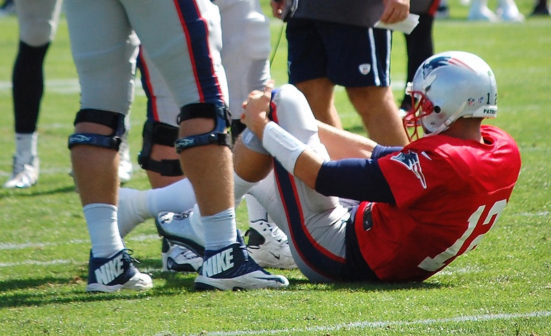 New England Patriots quarterback Tom Brady grabs his left knee after an apparent injury during a joint workout with the Tampa Bay Buccaneers at NFL football training camp in Foxborough, Mass., on Wednesday.