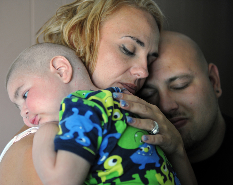Christine Swidorsky holds her son, Logan Stevenson, 2, with her husband-to-be and Logan's father Sean Stevenson, for a portrait in their Jeannette, Pa., home July 30.
