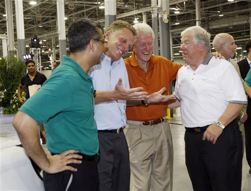 In this July 6, 2012, photograph, then-GreenTech Automotive executive Terry McAuliffe, second from left, jokes with former President Bill Clinton, center, and former Mississippi Gov. Haley Barbour, following the unveiling of the new electric MyCar at their manufacturing facility in Horn Lake, Miss. The big plans of eventually hiring a workforce of 25,000 people and eventually producing 1 million cars a year have been scaled back to a smaller facility to make 30,000 electric vehicles a year.
