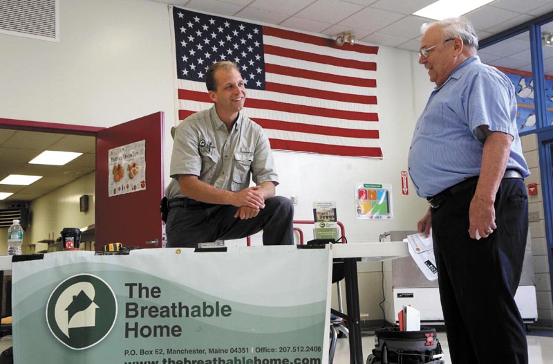 Bo Jespersen, owner of The Breathable Home in Manchester, chats with Allan Laney of Norridgewock, right, at a free energy exposition at Madison Area Memorial High School today. Jespersen's business specializes in energy retrofits and energy audits.