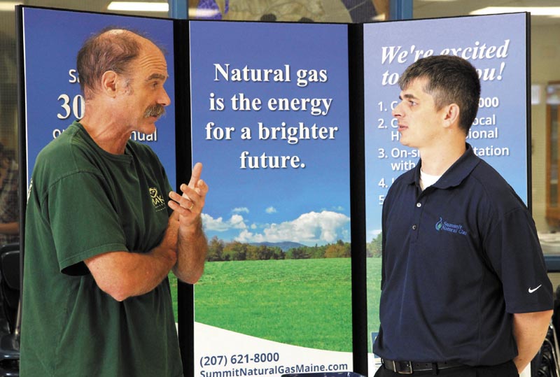 Ernie Hilton, left, of Starks, chats with Summit Natural Gas sales representative Ryan Wheaton at a free energy exposition at Madison Area Memorial High School today.