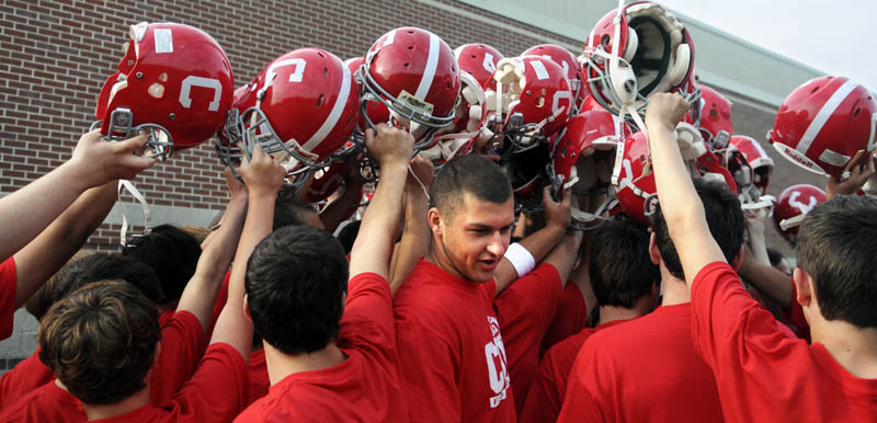 GOOD DAY: Cony High School quarterback Ben Lucas, center, raises his helmet with teammates on Monday during the first morning of football practice.