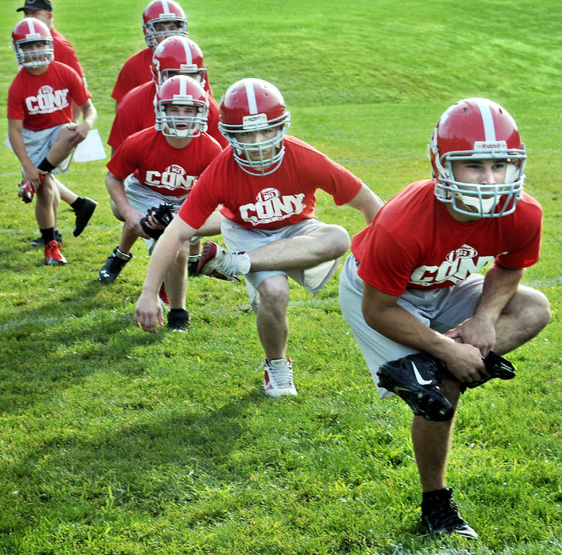 IT BEGINS: Cony High School football player John Bennett, right, leads his squad in a stretch during the first morning of football practice Monday at Cony High School in Augusta.