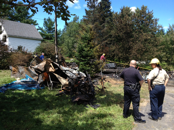 Investigators from the Office of the State Fire Marshal and Richmond Police examine the remnants of a mobile home that burned Sunday night on Kimball Street in Richmond.