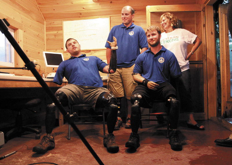 Quadruple amputee Travis Mills, left, talks to reporters with fellow wounded veterans Taylor Morris, right, and Drew Mullee, top, as Maine's First Lady Ann LePage looks on at Camp Kennebec in Belgrade on Wednesday night. This week is "Founder's Week" at the Travis Mills Project National Veterans' Family Center at the camp located on the shores of Salmon Lake.