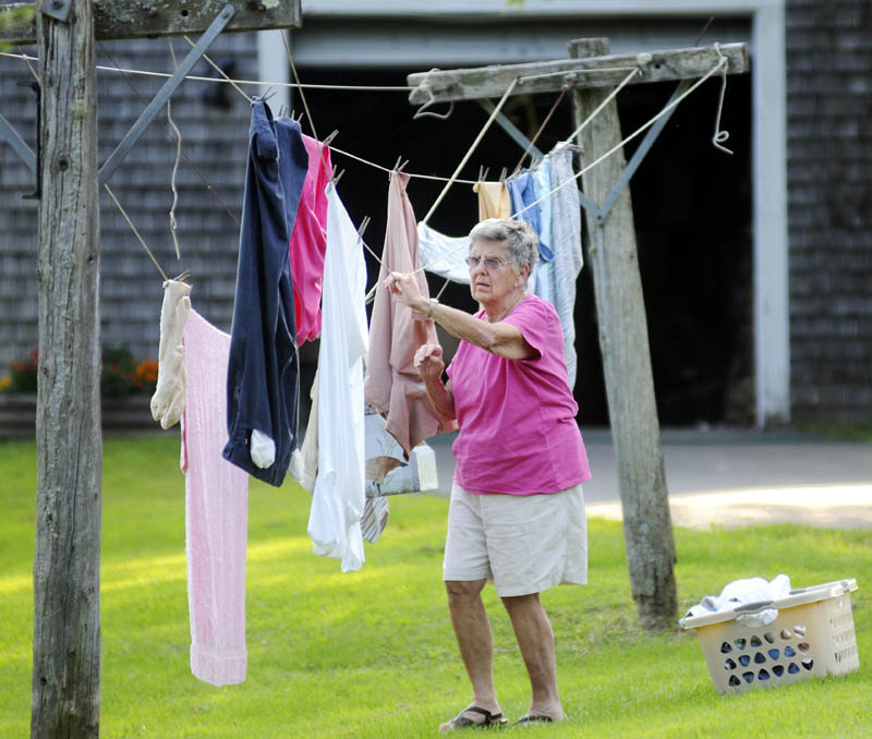 Lillian Palleschi takes down the laundry Thursday at her family's Monmouth farm. The 83-year-old was attending to the wash while her husband, Everett, who will be 83 on Saturday, tilled over weeds in their garden in 90-degree temperatures.