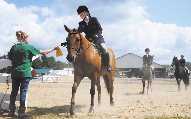 Katelyn MacMaster, left, hands Rayelyn Spencer a ribbon today during the 4-H horse show at the Windsor Fair. Several dozen riders showed off their steeds during the event, held on the fourth day of the annual agricultural exhibition.
