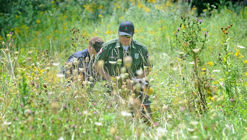 Lt. Kevin Adams, foreground, of the Maine Warden Service, state police Trooper Shawn Porter and search dog Myka emerge from the woods near Skowhegan's Reddington-Fairveiw General Hospital on Fairview Avenue shortly after finding the body of Vaughn Giggey III on Tuesday.