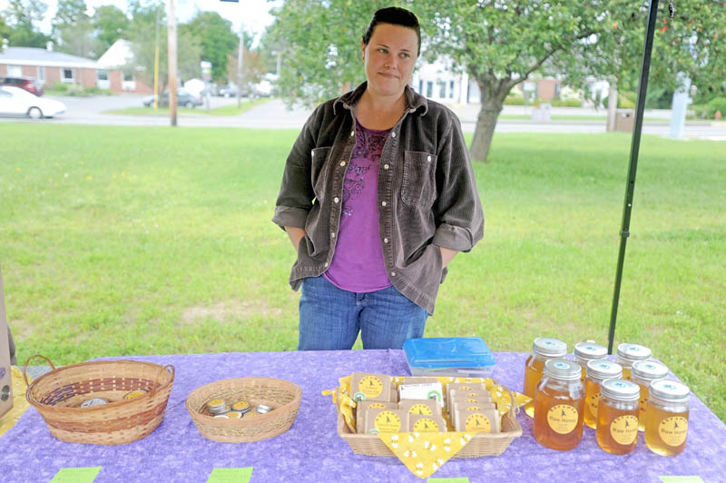 Samantha Burns, owner of Runamuk Acres in Anson, stands by some of her bee-friendly products at the Madison farmers market at a new park on Main Street today.