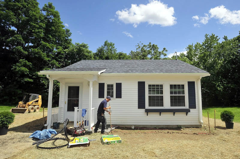 Sam Tieman landscapes the front of the newly built microhome at 20 Cool St. in Waterville on Tuesday. The energy-efficient dwelling has one bedroom and a full bathroom, complete with washer and dryer hook-ups. The building's total utilities cost for a year is estimated at $400.