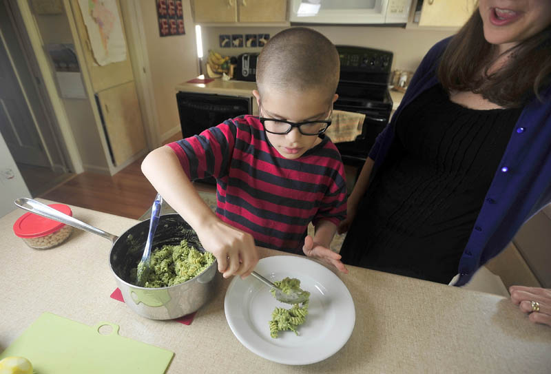 Noah Koch, 9, and his mother, Hilary, of Waterville, prepare his award-winning pesto in their Waterville home today.