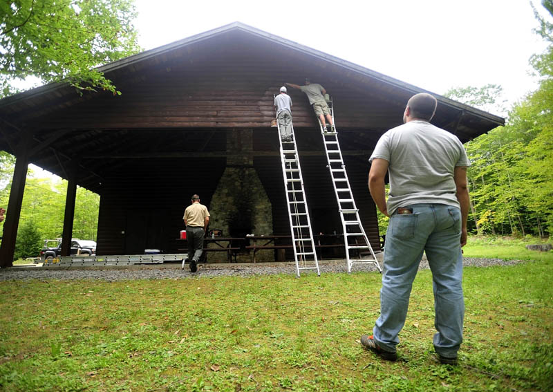 Matt Cowan, on the ladder at left, and Mat Gross, on the ladder at right, put a fresh coat of paint on the Margaret Chase Smith Hall at Lake George Regional Park on the Canaan and Skowhegan town line today as Backyard Farms coworker Matt Abbott, foreground, watches. The crew from Backyard Farms has been volunteering time at Lake George Regional Park, helping with maintenance and general upkeep of the facility.