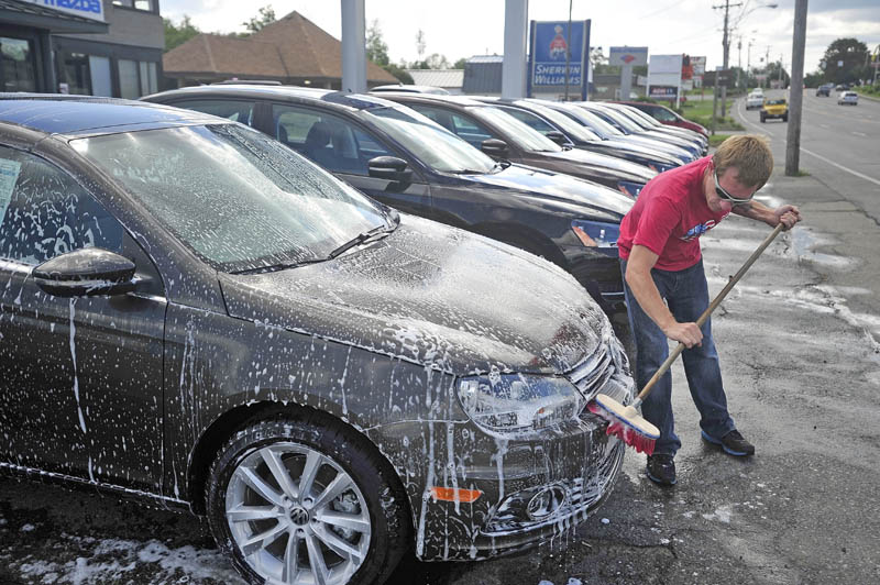 Dominic Frost, 31, washes one of the estimated 125 cars on the lot at Thompsons Audi / Volkswagon on Main Street in Waterville today. The weather and a second set of hands from helper Sander Spensson moved the process along rather quickly.