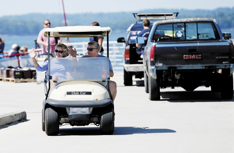 Camille and Wes Wolfertz, of Long Island, wave as they drive their golf cart from the dock at Long Island after a trip to the main land for supplies Thursday.