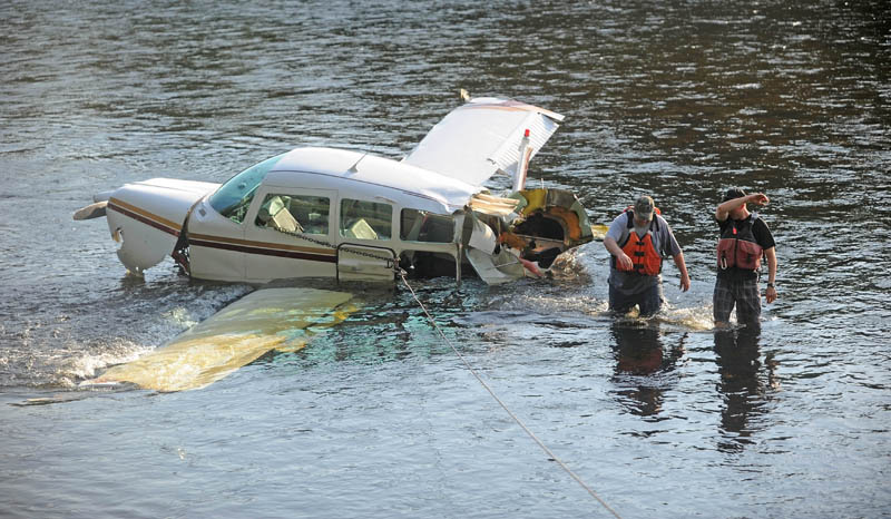 Charles Robins, left, of Charlie and Sons garage and Chad Robertson, right, with the Maine Warden Service, prepare to haul a single-engine Beechcraft airplane from the Kennebec River today, after it crashed on take-off from Gadabout Gaddis Airport in Bingham. The aircraft was piloted by Ray Ayer, 59, of Monmouth, and had one passenger, Paul Householder, 54, of Wayne. No injuries were reported.