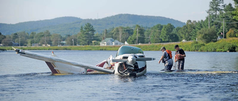 Charles Robins, left, of Charlie and Sons garage and Chad Robertson, right, with the Maine Warden Service prepare to haul a single-engine Beechcraft airplane from the Kennebec River after it crashed shortly after takeoff from Gadabout Gaddis Airport in Bingham today.