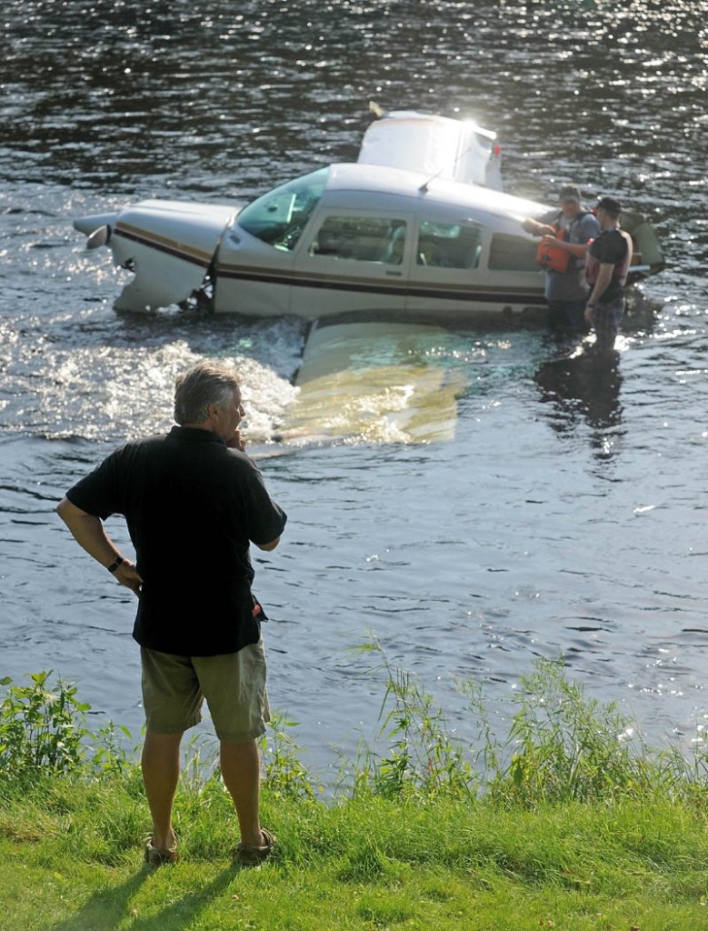 Ray Ayer, 59, of Monmouth, stands on the banks of the Kennebec River as crews try to secure a cable to a disabled airplane he piloted, after it crashed into the Kennebec River in Bingham today.