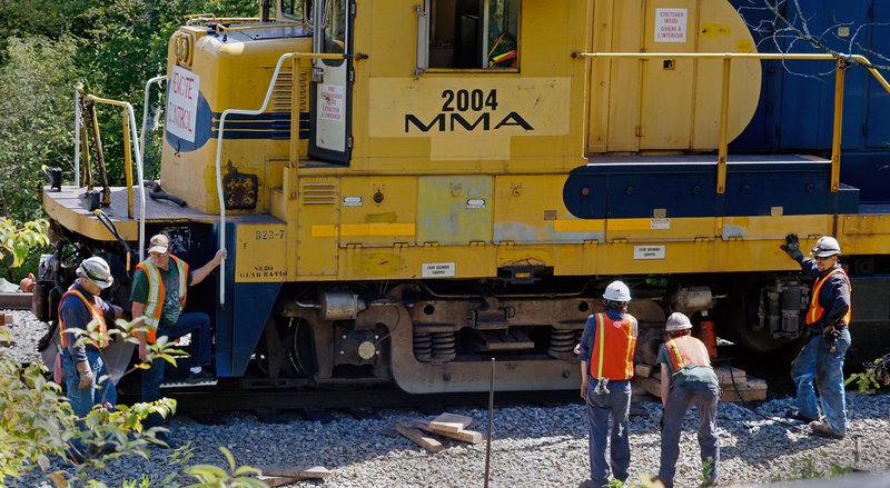 A crew from Montreal, Maine & Atlantic Railway works to put a derailed locomotive back on the tracks in Brownville on Wednesday, July 31, 2013. The Maine-based company filed for bankruptcy Wednesday, Aug. 7, 2013, just 33 days after one of its unattended trains rolled down a hill and derailed, causing explosions that killed 47 people in Lac-Megantic, Quebec.