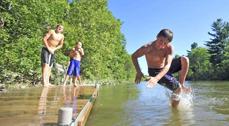 Anthony Visconti, 14, of Waterville, leaps in to the water from the dock on the Messalonskee Stream on North Street in Waterville on Saturday. The dock has become a popular place for locals to find respite from the heat.