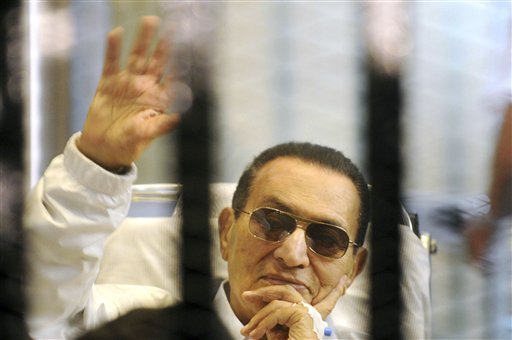 Former Egyptian President Hosni Mubarak waves to his supporters from behind bars as he attends a hearing in his retrial on appeal in Cairo in this April 13, 2013, photo.