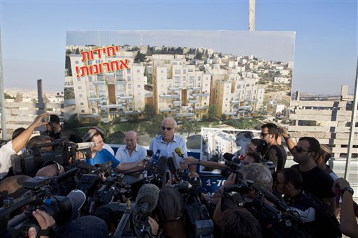 Israeli Minister of Housing and Construction Uri Ariel, center, speaks to journalists during a ceremony to mark the resumption of the construction of housing units in an east Jerusalem neighborhoodtoday. Israel's housing minister today gave final approval to build nearly 1,200 apartments in Jewish settlements, just three days before Israeli-Palestinian peace talks are to resume in Jerusalem. Hebrew on the sign reads "Last Units."