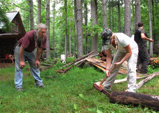 Eustace Conway, left, offers encouragement as a camper hammers a wedge into a log at his Turtle Island Preserve in Triplett, N.C., on June 27. People come from all over the world to learn natural living and how to go off-grid, but local officials ordered the place closed over health and safety concerns.