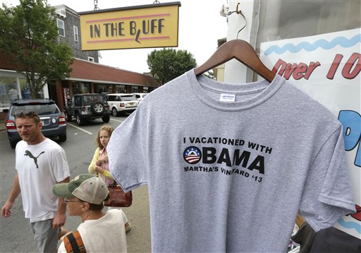 Passers-by walk past a souvenir T-shirt with President Barack Obama's name, right, at a shop in Oak Bluffs, Mass., on the island of Martha's Vineyard, on Friday. The first summer vacation of President Obama's second term is bringing him back to Martha's Vineyard, the well-heeled Massachusetts island.