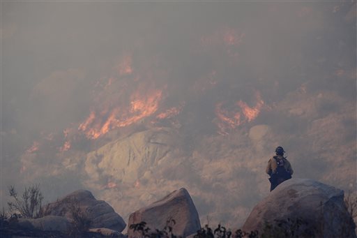 A firefighter watches a backfire burn while battling a wildfire in Banning, Calif.