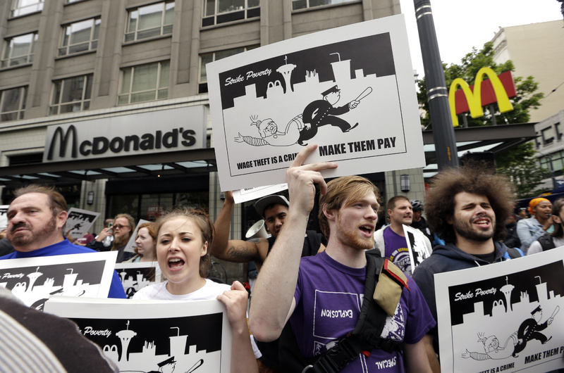 Demonstrators protesting what they say are low wages and improper treatment for fast-food workers stand near a McDonald's restaurant in downtown Seattle earlier this month.