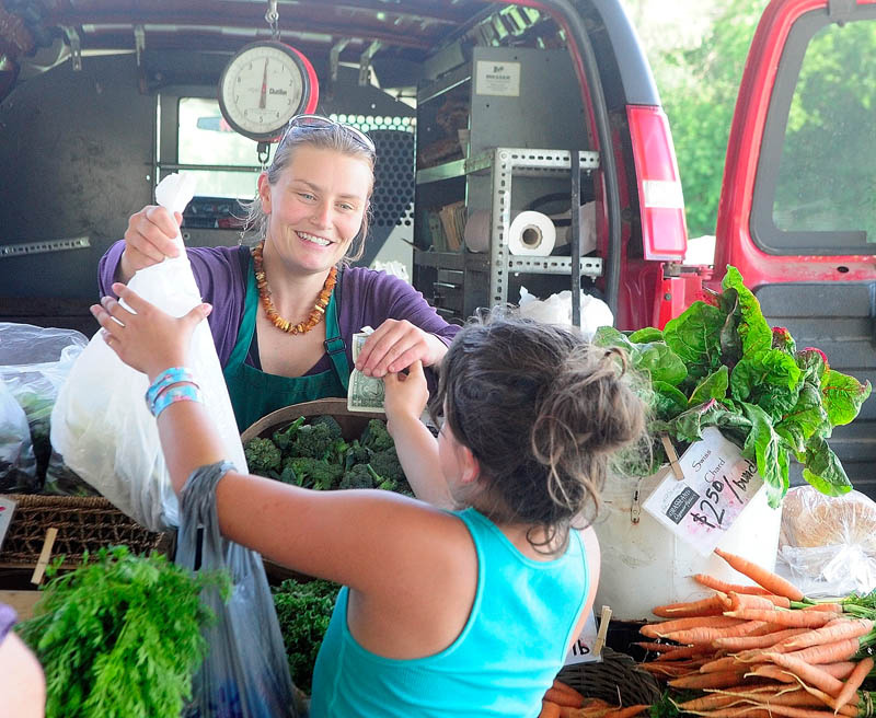 Sarah Smith, of Grassland Organic Farm in Skowhegan, left, sells beans to Shania Willette, 11 of Chelsea, on Tuesday at the Farmers Market in Mill Park in Augusta.