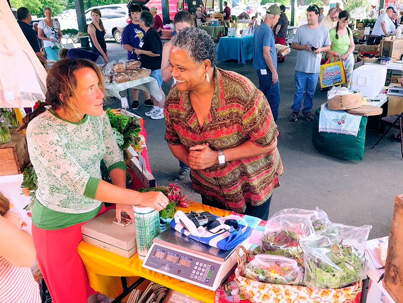 Farmer Dalziel Lewis, left, chats with customer Gloria Payne, of Augusta, at the Dig Deep Farm booth on Tuesday at the Farmers Market in Mill Park in Augusta.