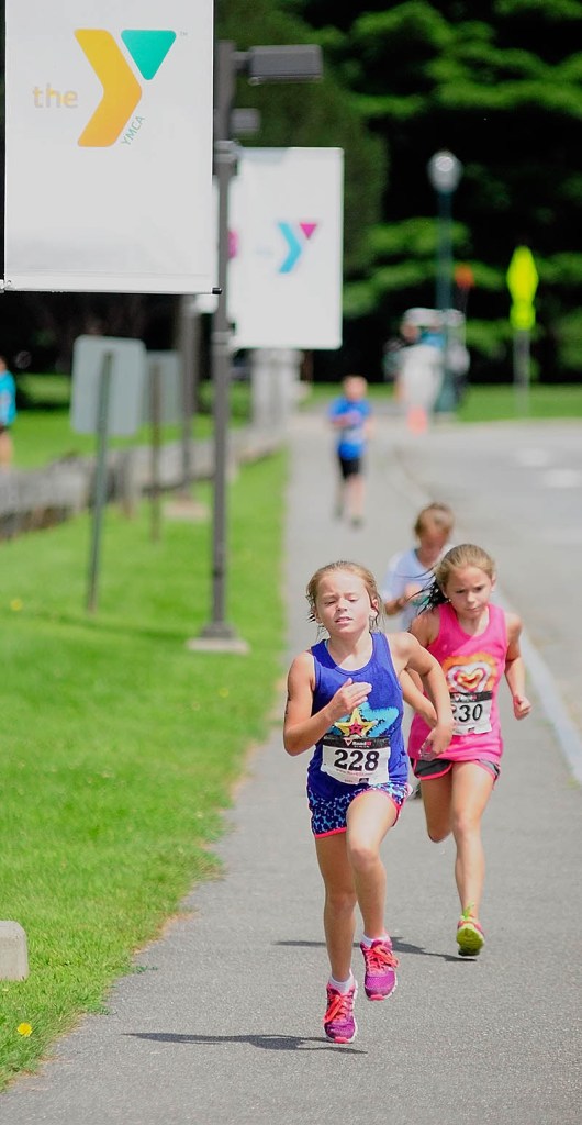 Kristen Kirk, left, and Grace Kirk sprint for the finish line during the youth division race of the Capital Y Tri today in Augusta. Grace Kirk won the 8-to-9-year-old girls division with a time of 15:50.1, edging out Kristen Kirk, at 15:50.4.