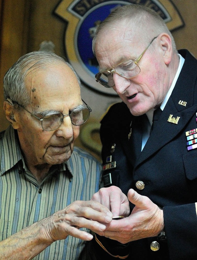World War II veteran Al Kramer, of South China, left, and Peter W. Ogden, Director of the state's Bureau of Veterans' Services, look at a commemorative coin given to Kramer during a ceremony on Thursday in Augusta.
