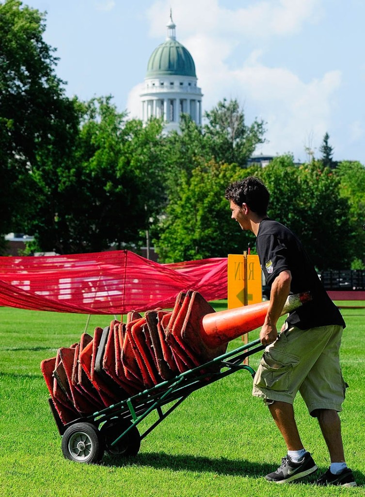 Curtis Coleman rolls cones into position today as the crew from All Sports Events sets up the transition and finish area for the Capital Y Tri , between the Kennebec Valley YMCA and the State House in Augusta. The inaugural event starts at 7 a.m. Saturday for adult competitors, followed by a children's triathlon. Adults will swim 425 yards in the pool, then bike 11 miles before finishing with a 3.1 mile run.