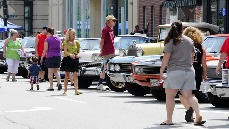 People look over a row of antique cars parked along Water Street today during AugustaFest 2013 in downtown Augusta. There was live music, food, art booths and a climbing wall set up a along the street and at the Augusta Waterfront Park.