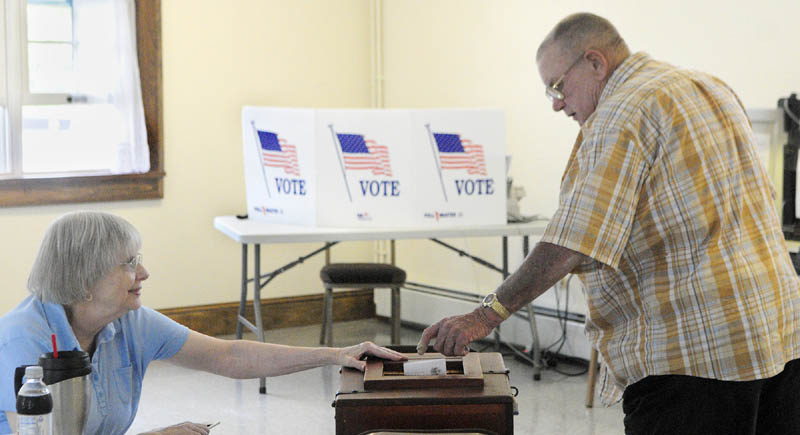 Ballot clerk Mary Haven, left, holds open the box as Bob Gleason drops in a ballot today, during the special Senate District 19 election at Pownalborough Hall in Dresden.