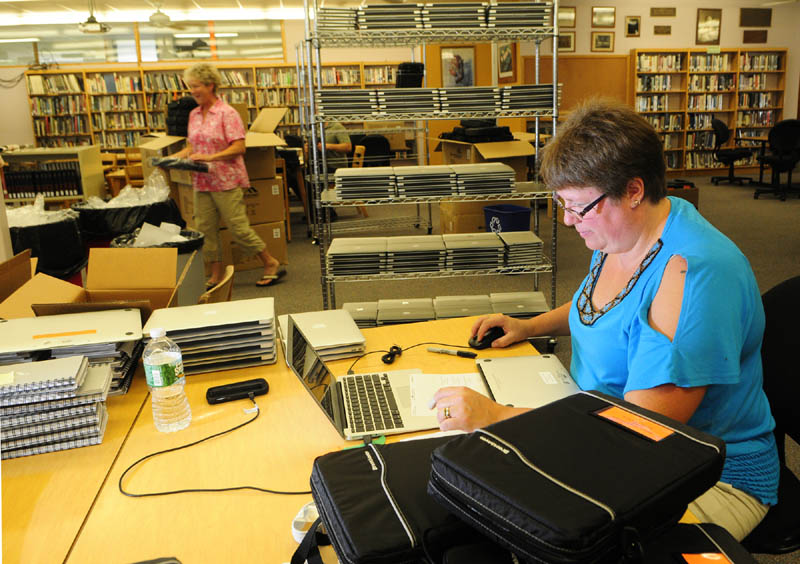Melissa Gregoire puts an Apple MacBook Air into a carrying case on Wednesday at Gardiner Area High School in Gardiner. Gregoire and other workers were preparing the 732 new laptops that will issued to all students and staff at the high school for the coming school year.