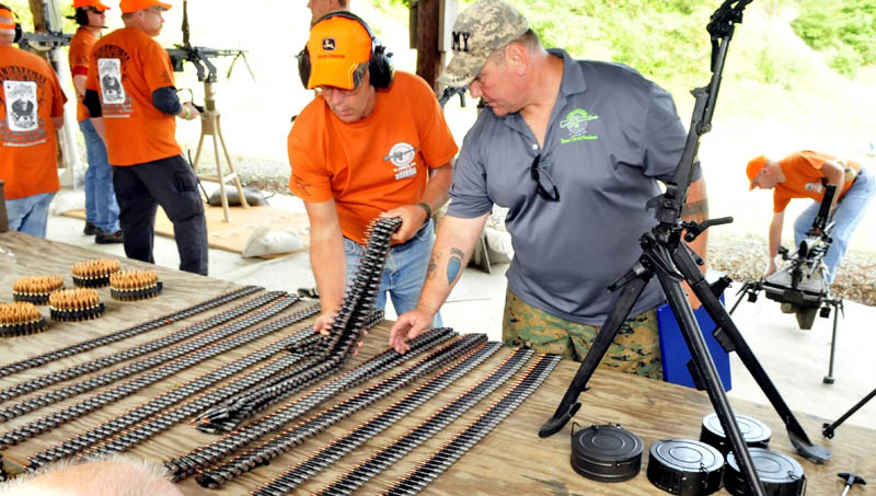 Andy Williams, right, and a volunteer load automatic weapons with ammunition belts during the Wounded Warriors Machine Gun Shoot in North Anson today. Williams hosts the event to bring veterans and gun enthusiasts together to socialize.