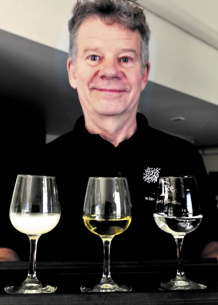Bruce Olson, co-owner of Tree Spirit Winery, holds a tray of absinthe in different stages of production at the Oakland company. At left is a glass of absinthe in the Louche phase, a more flavorful version that turns white after water is added. The center glass is the finished version that is more potent, with a green tint from added herbs. At right is the clear, beginning phase.