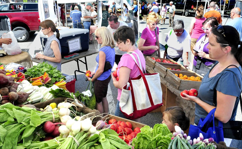 Customers, including Sharon Bushey, center, wait in line to buy fresh produce at the booth of Cornerstone and Fail Better farm, in Palmyra, at the Waterville Farmers Market on Thursday.