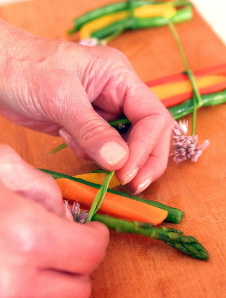 Cheri Savage, owner of The Heritage House in Skowhegan, uses chives to make a vegetable bundle today, to be served at a sit-down dinner at Wednesday's Taste of Greater Waterville.
