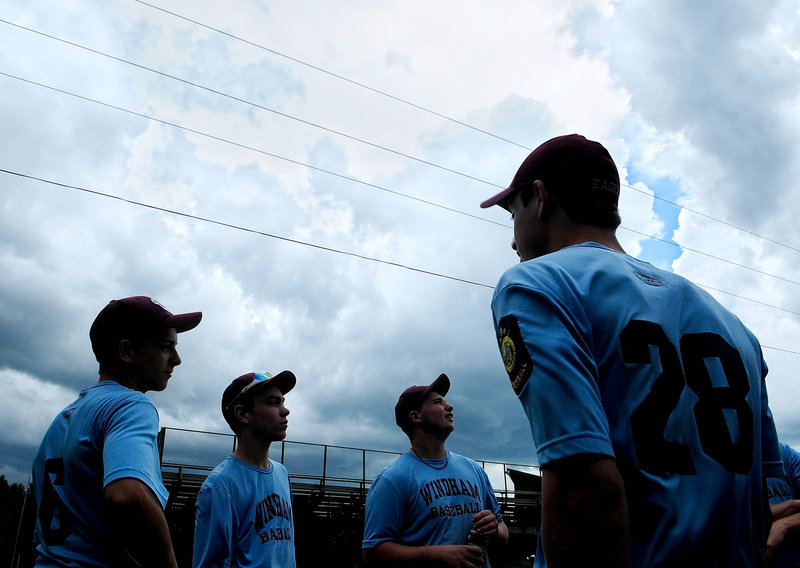 With storm clouds moving in, Windham players wait Sunday to find out if the American Legion baseball state championship game in Augusta would be postponed. It was, so Windham will play for the title Monday against Saco & Biddeford Savings of Westbrook.