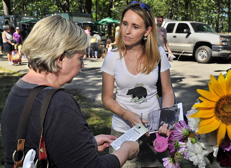 Katie Hansberry of the Maine chapter of the Humane Society hands out pamphlets at the farmers market in Portland’s Deering Oaks park Saturday. Animal-welfare advocates want to ban three bear-hunting methods: baiting; using dogs; and using snare traps.